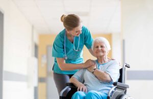 A caregiver assisting a senior in washing hands at a bright, clean shared bathroom sink.