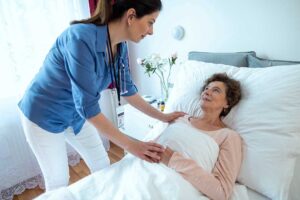 Older couple speaking with a caregiver in a bright assisted living room, with personal photos and a care plan nearby.