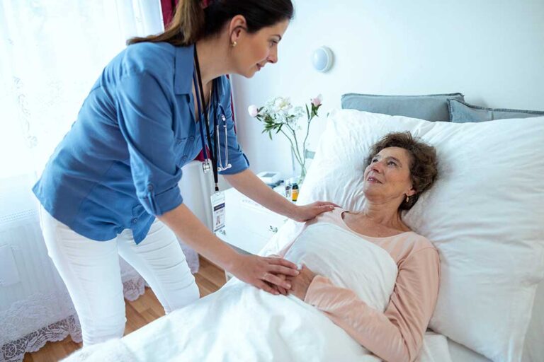 Older couple speaking with a caregiver in a bright assisted living room, with personal photos and a care plan nearby.
